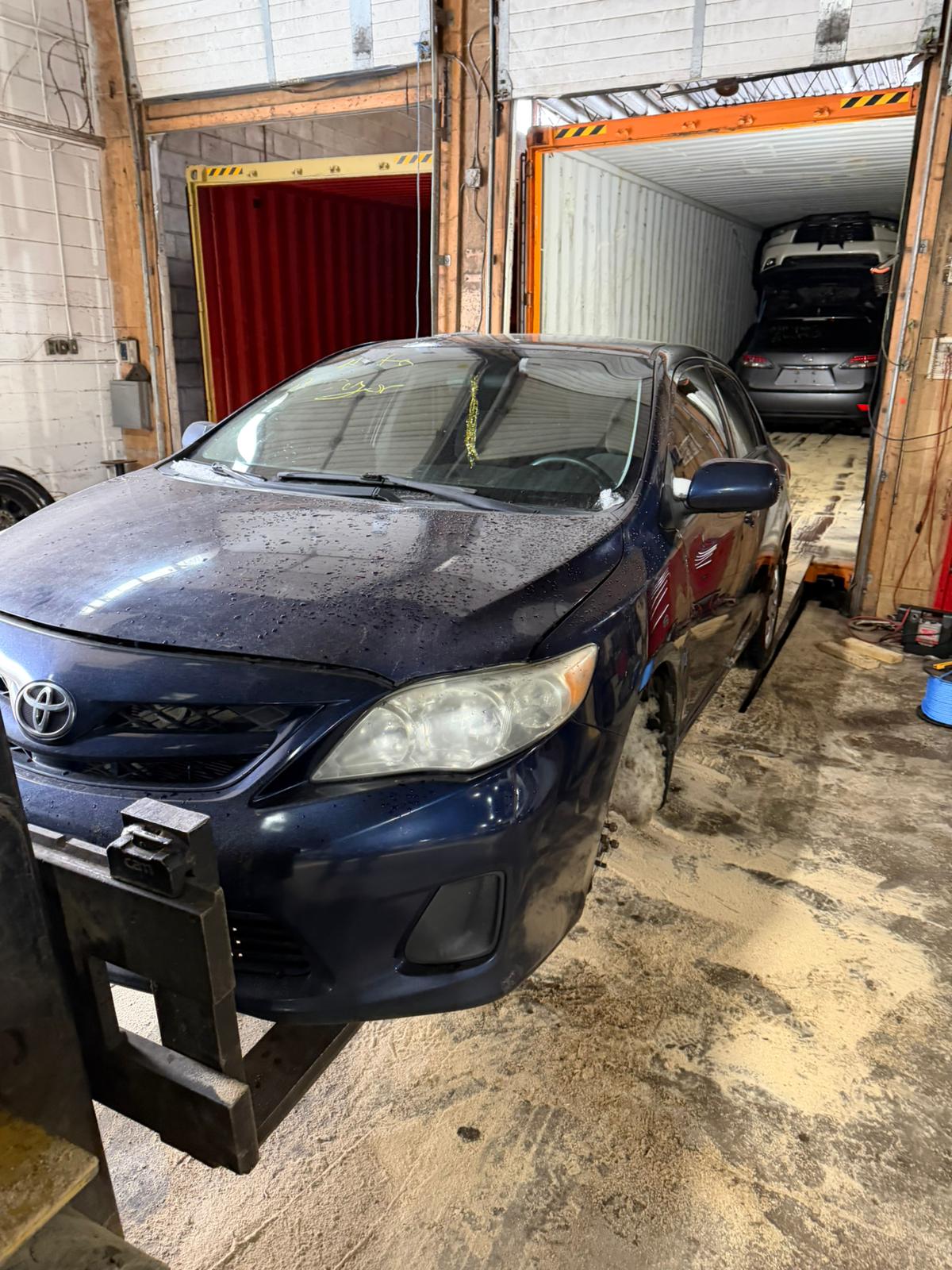 Toyota Corolla being loaded into a shipping container in Canada